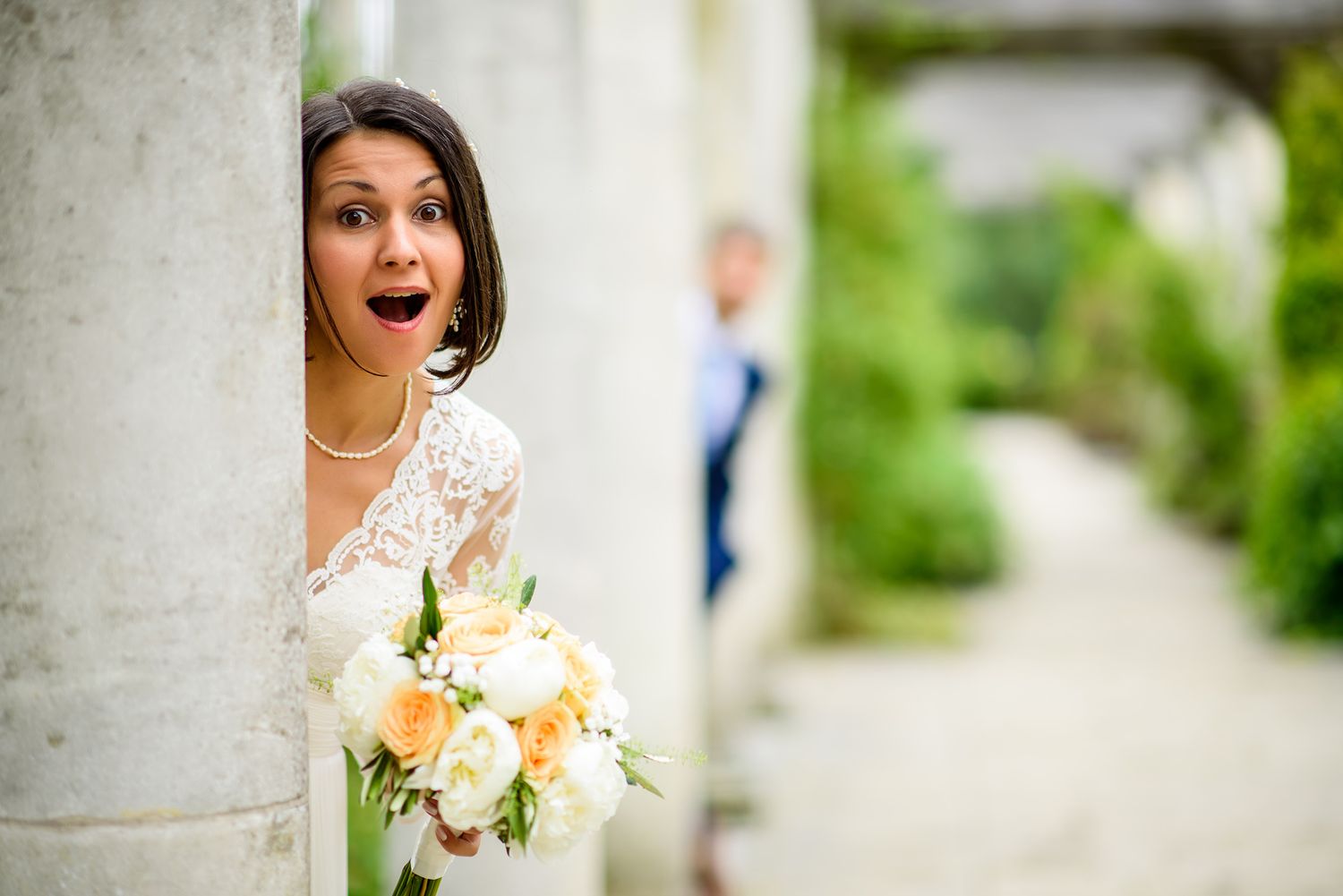 Couple takes romantic portraits in a garden pergola setting with white columns.