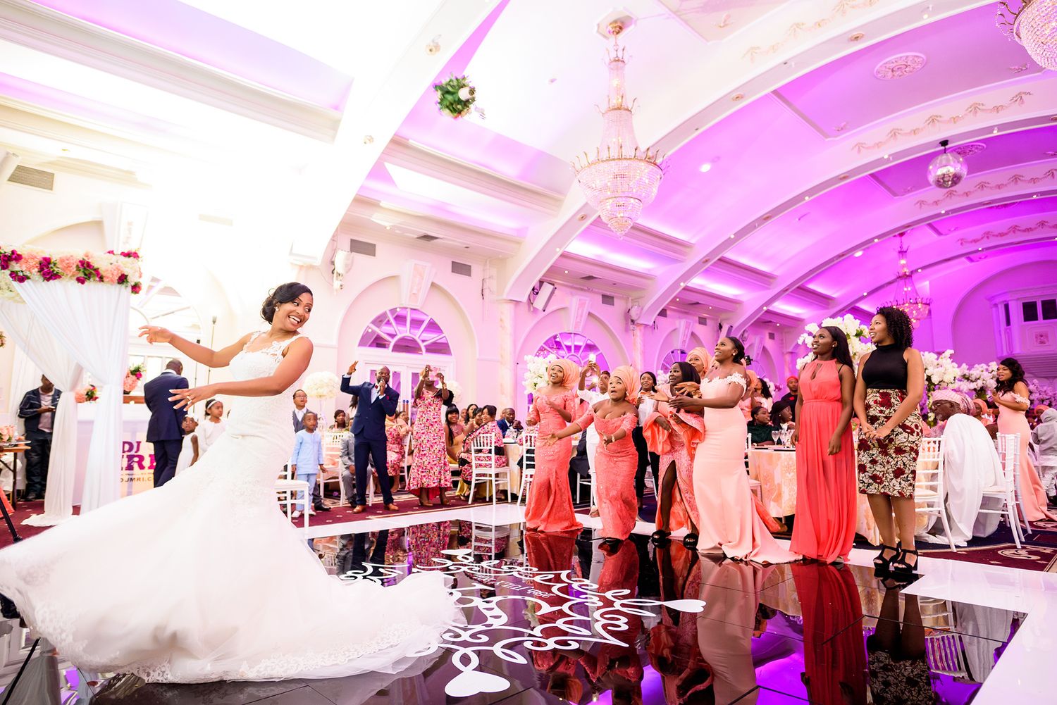 Wedding reception dance floor filled with celebrating guests under purple mood lighting.