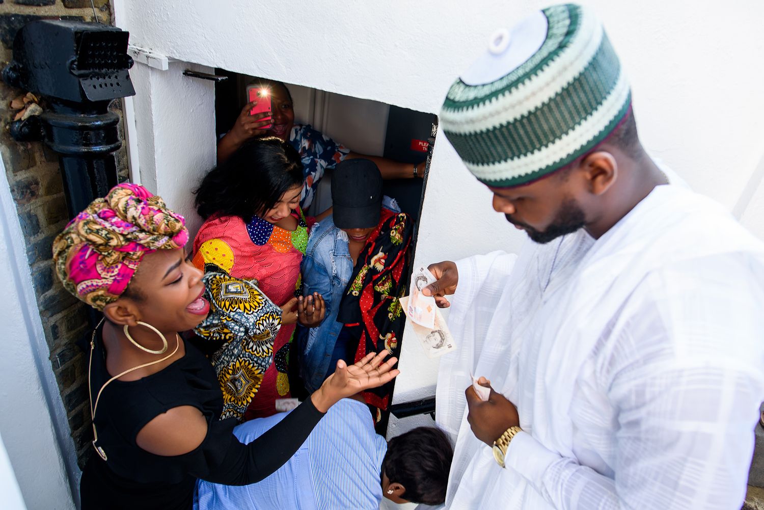 People in traditional and colorful attire gathered outside a building entrance.