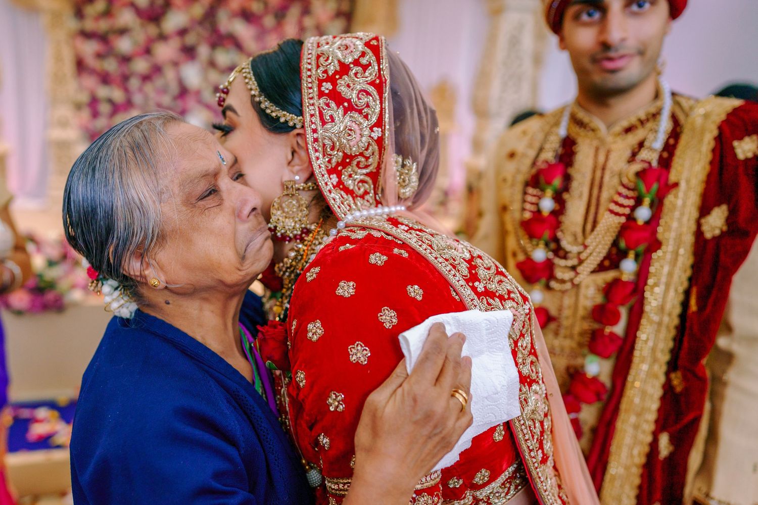 Traditional Indian wedding ceremony with guests wearing vibrant red and gold attire.