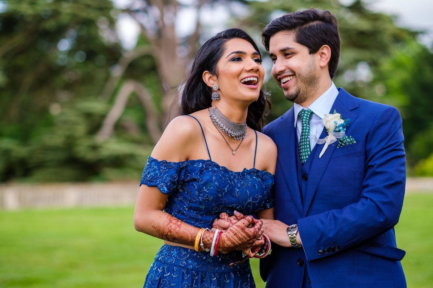 Couple in blue formal attire share joyful moment together on manor grounds.