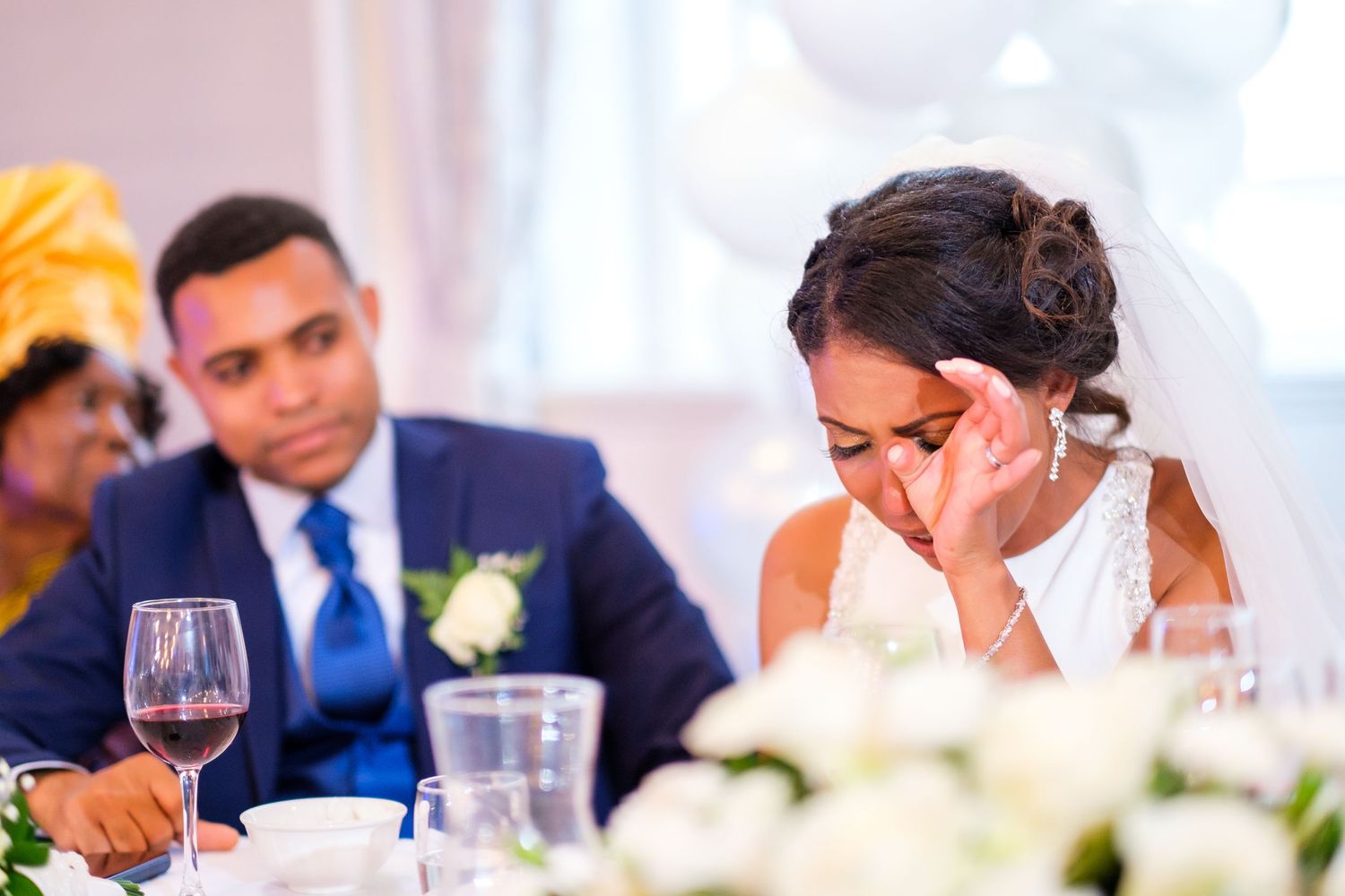 Wedding reception guests seated at elegant tables with wine glasses and floral centerpieces.