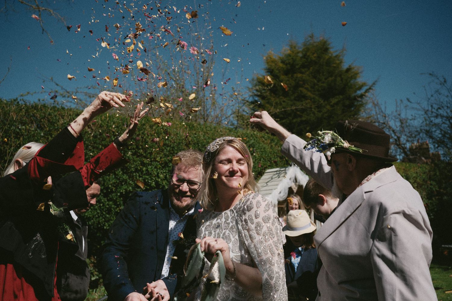 Joyous outdoor celebration with confetti flying against bright blue sky.