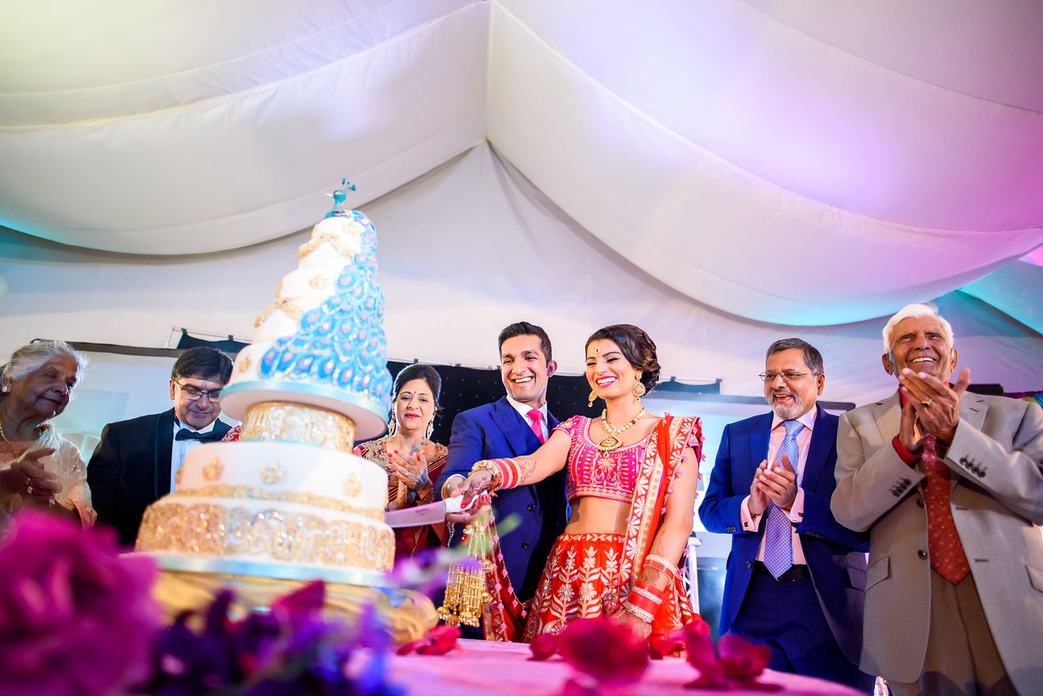 Wedding reception setup with elegant lighting and decorative elements under a white tent.