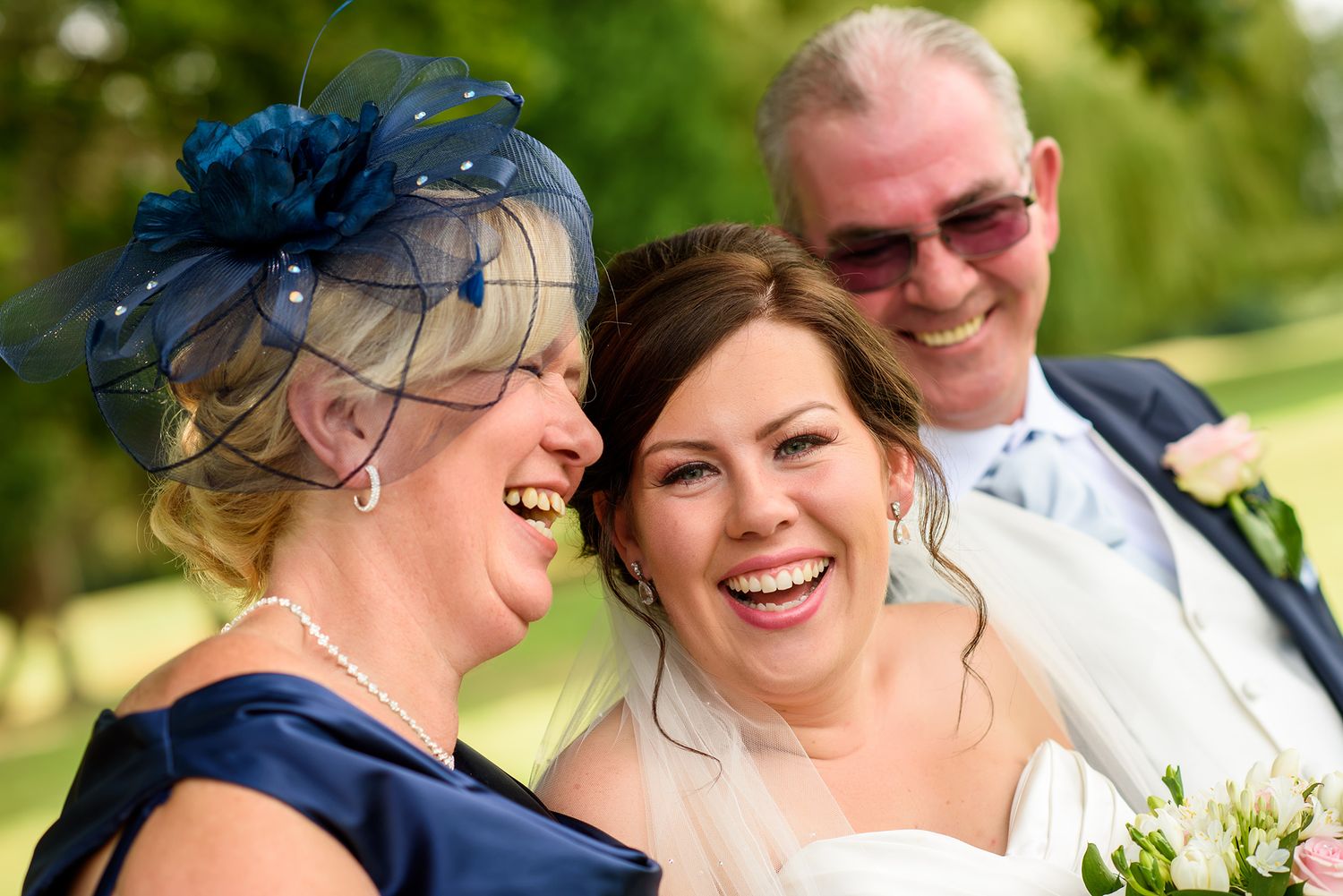 Wedding party shares genuine laughter and embraces during outdoor photo session.