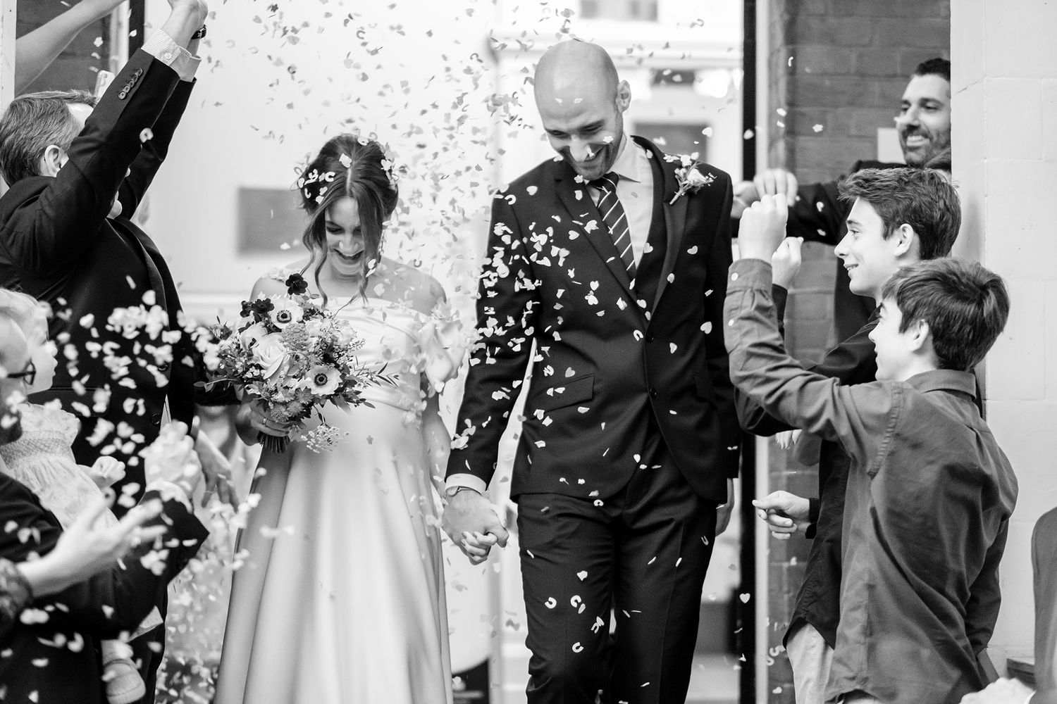 Joyful wedding celebration with confetti and natural light streaming through windows.