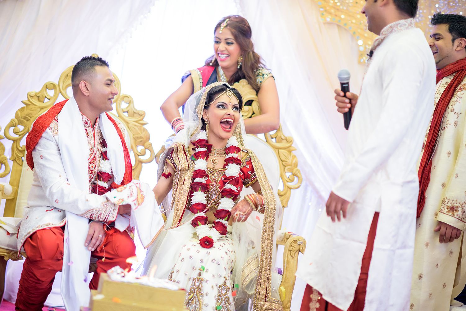 Wedding guests celebrating during a festive Indian ceremony with decorative gold backdrop.