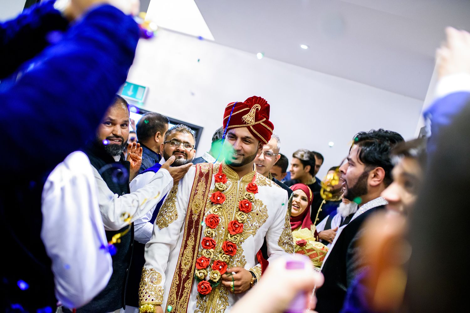 Guests celebrating at an Indian wedding ceremony with vibrant blue and red traditional attire.