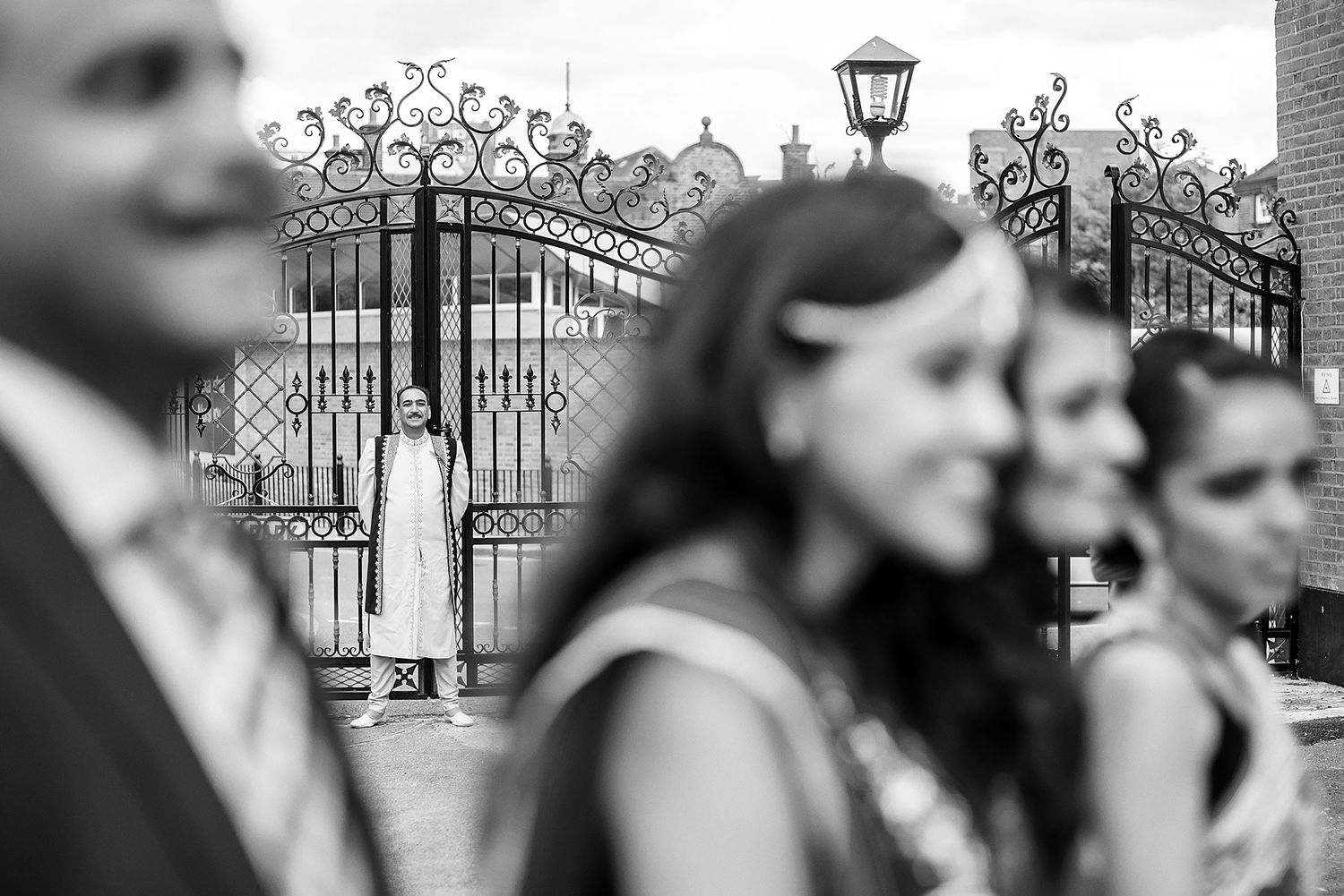 Black and white architectural detail of ornate gates and lamp posts at wedding venue.
