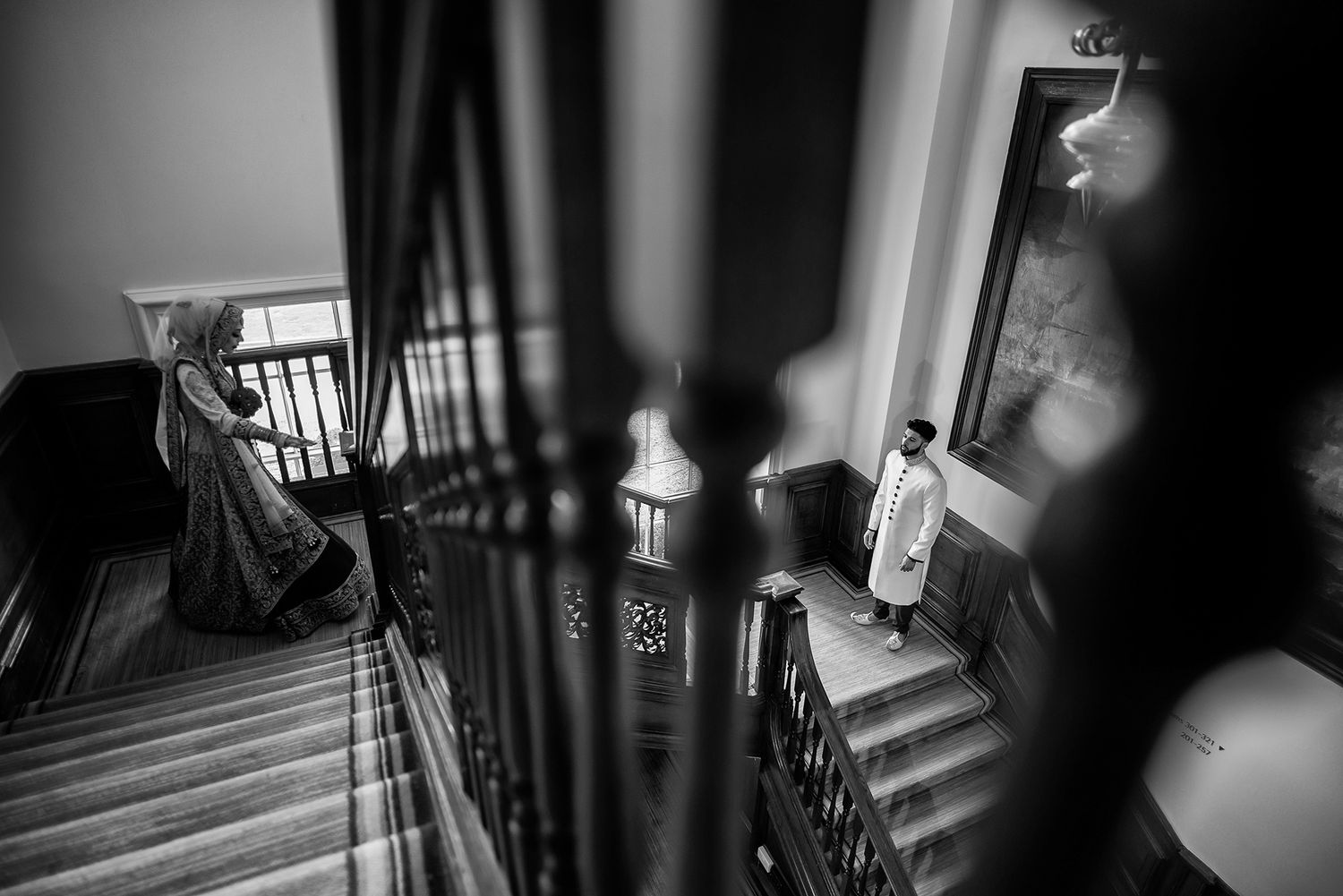 A dramatic black and white photograph of figures on a grand staircase with shadows.