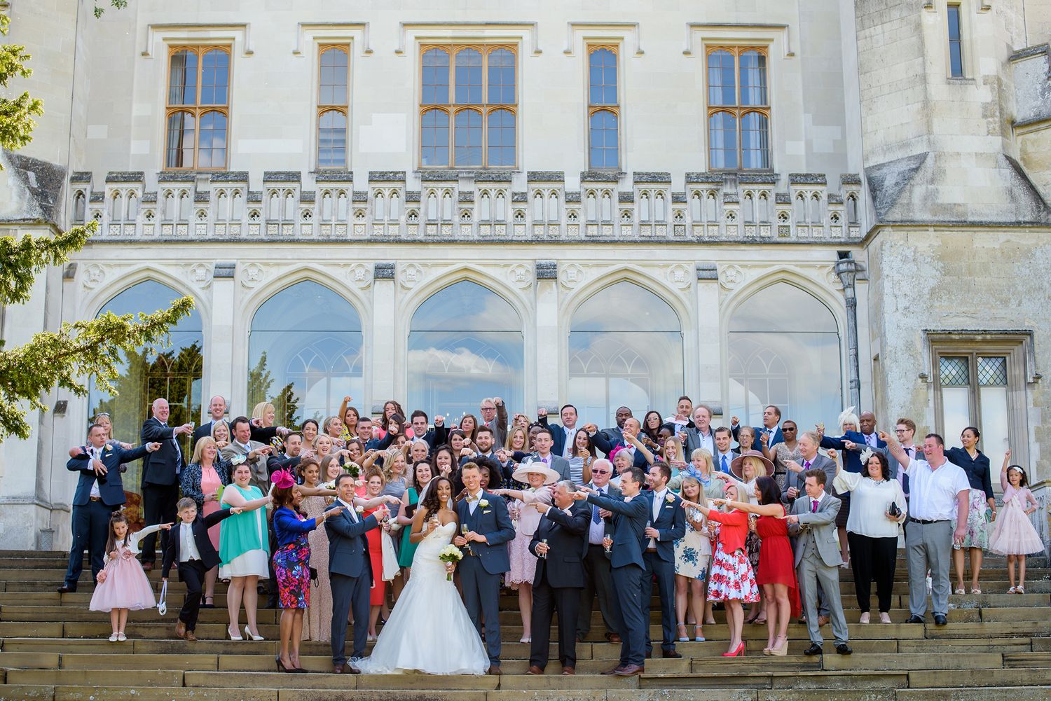 Large wedding group photo outside grand historic white mansion.