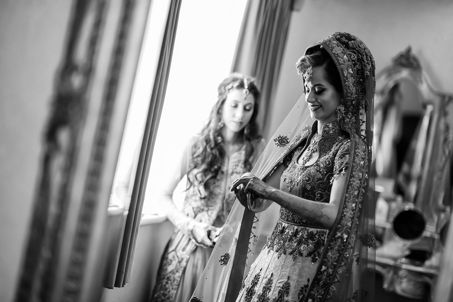 A black and white photo showing wedding preparation with traditional attire.