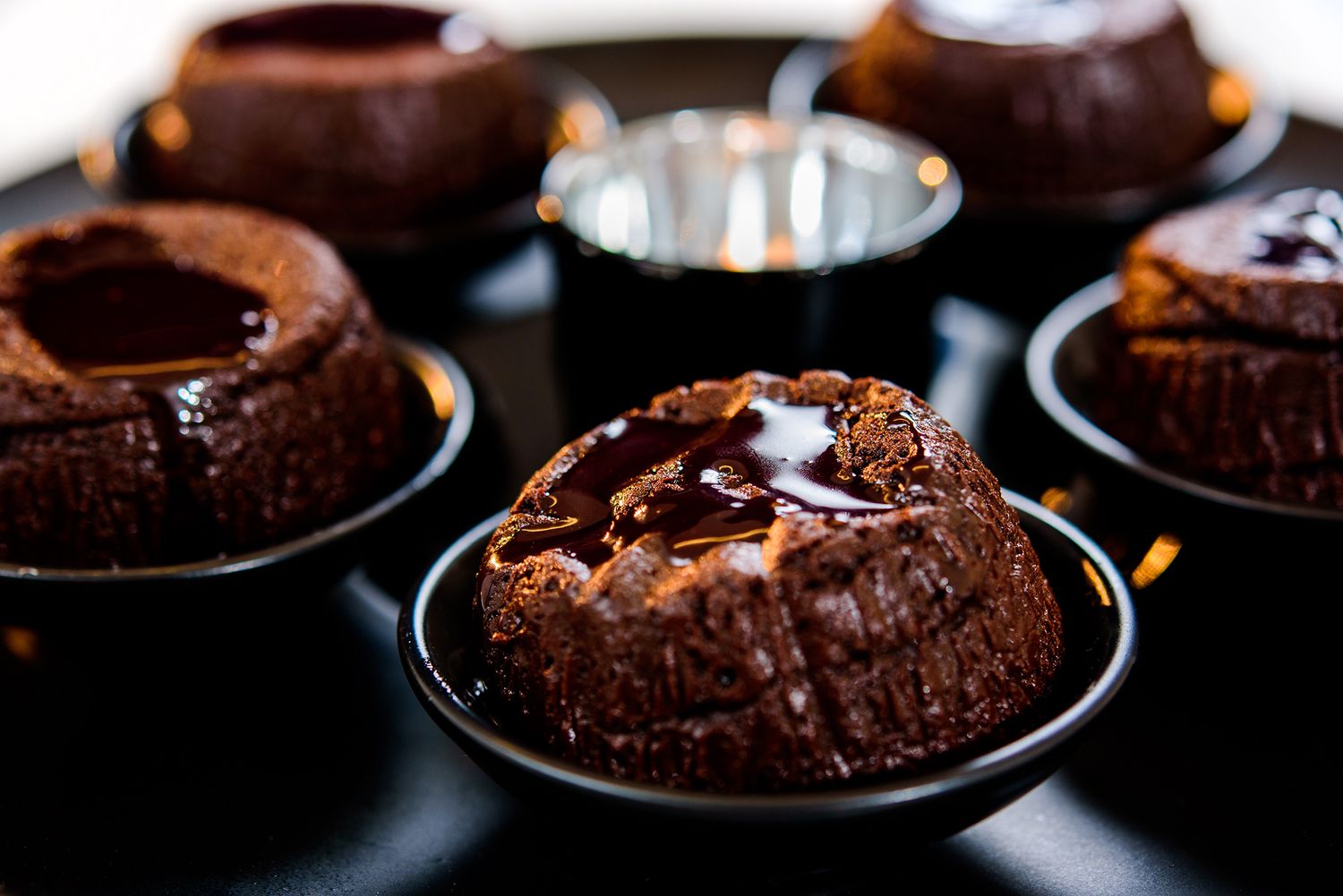 Row of chocolate lava cakes plated on dark dishes with molten centers.