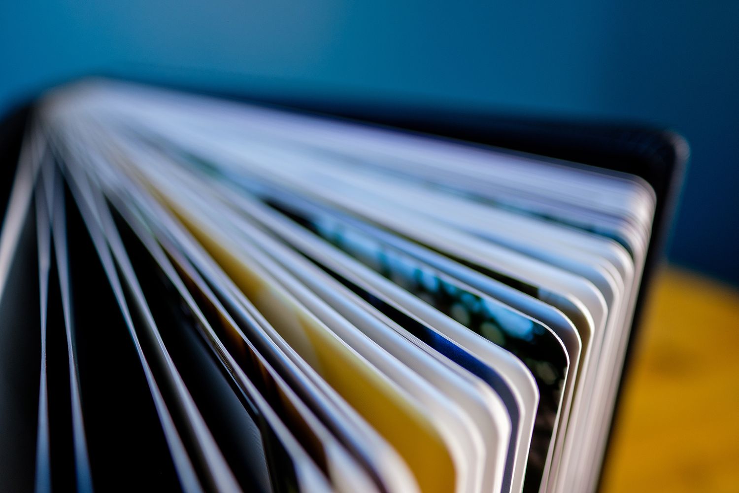 Side view of thick photo album pages fanned out showing white edges.