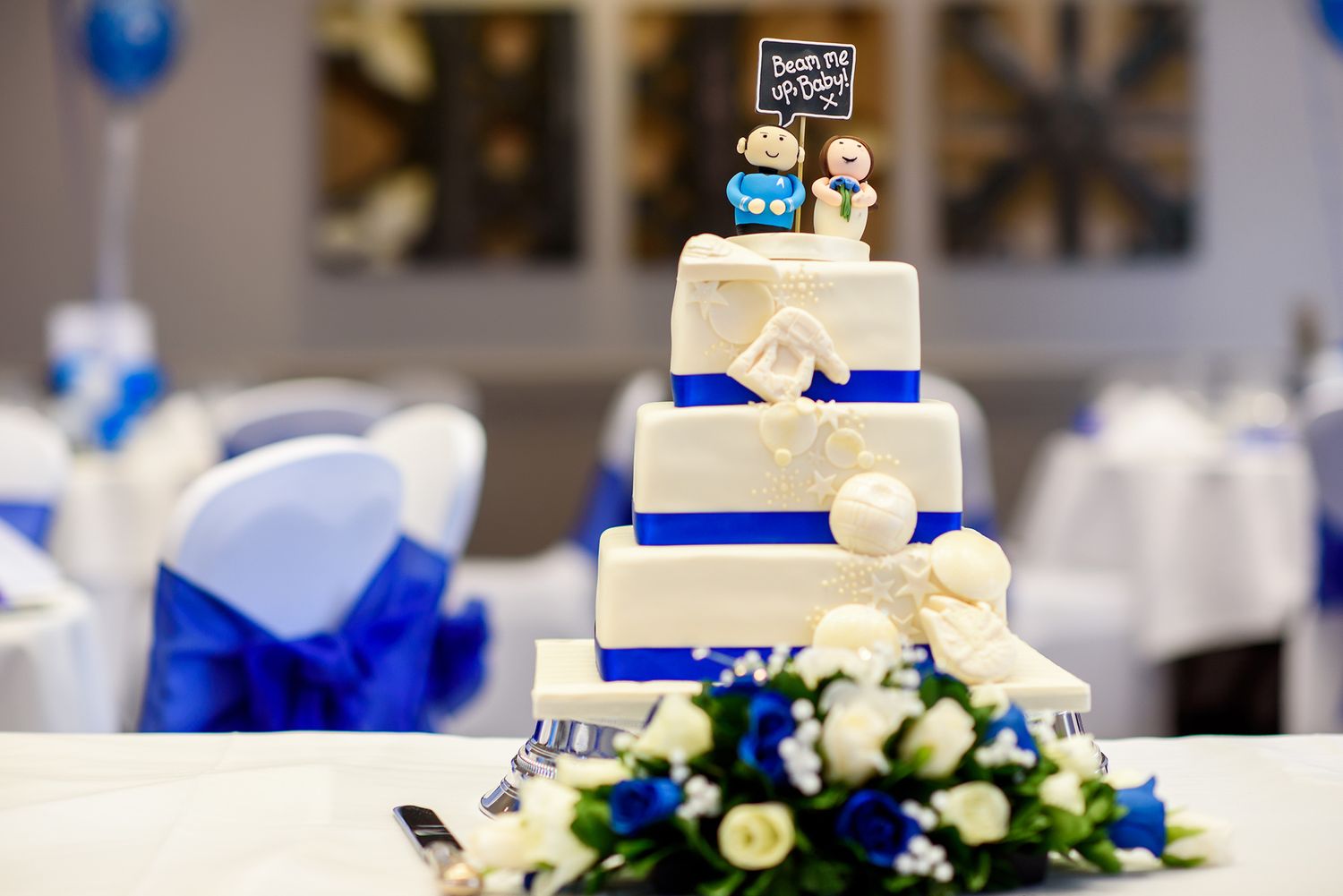 Wedding reception table with blue and white decorations and tiered cake.