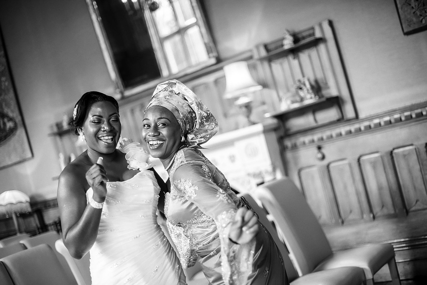 Black and white candid photograph showing wedding celebration filled with laughter and joy.