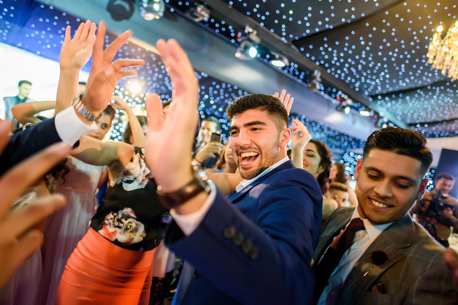 Partygoers celebrating under sparkling ceiling lights at formal evening event.