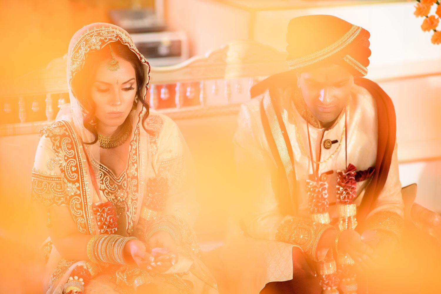 Warm orange-toned wedding photography capturing intimate moments during ceremony.