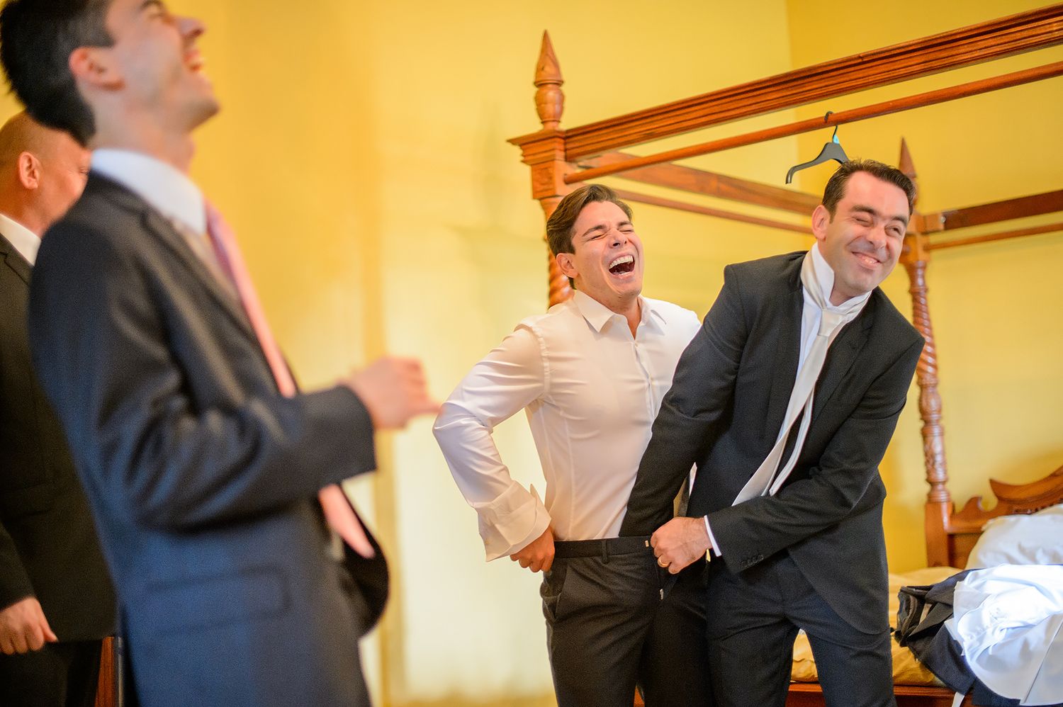 A row of candid shots showing wedding guests laughing and socializing in a warmly lit hallway.