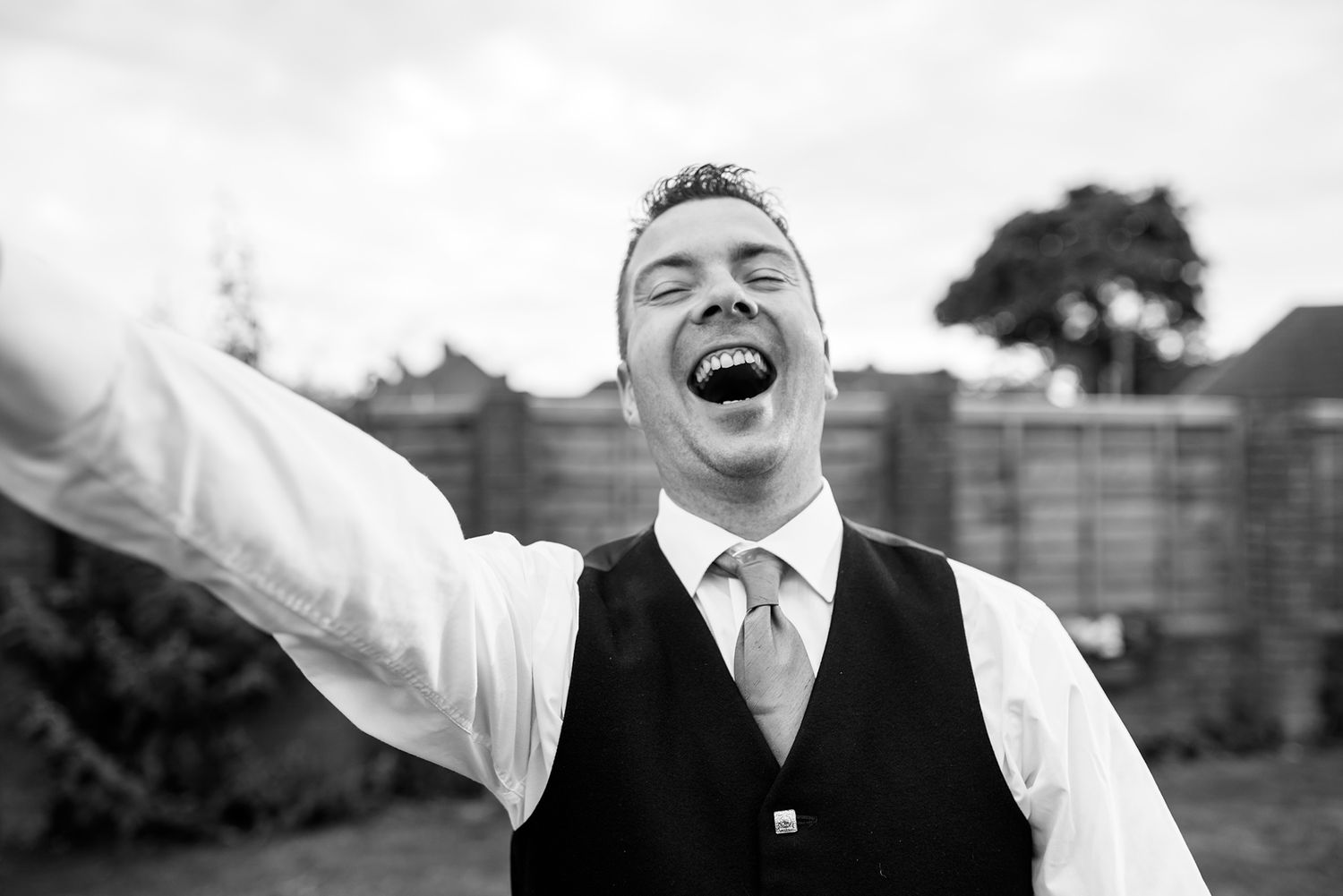 Joyful wedding party members pose expressively in black and white photography.