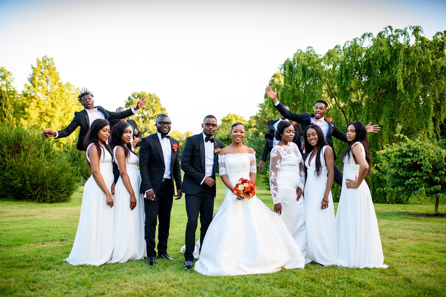 Wedding party poses together on green lawn with matching formal attire.