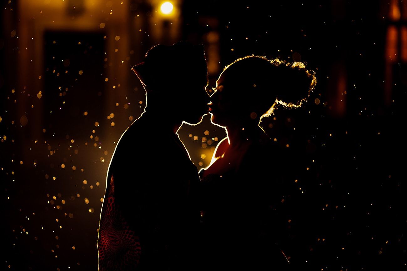 Romantic silhouettes against twinkling lights create a magical nighttime atmosphere.