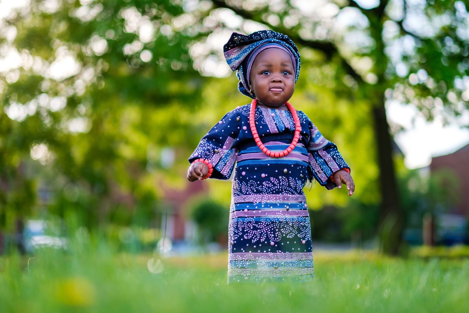 Cheerful child playing outdoors in bright blue outfit against lush green natural background.