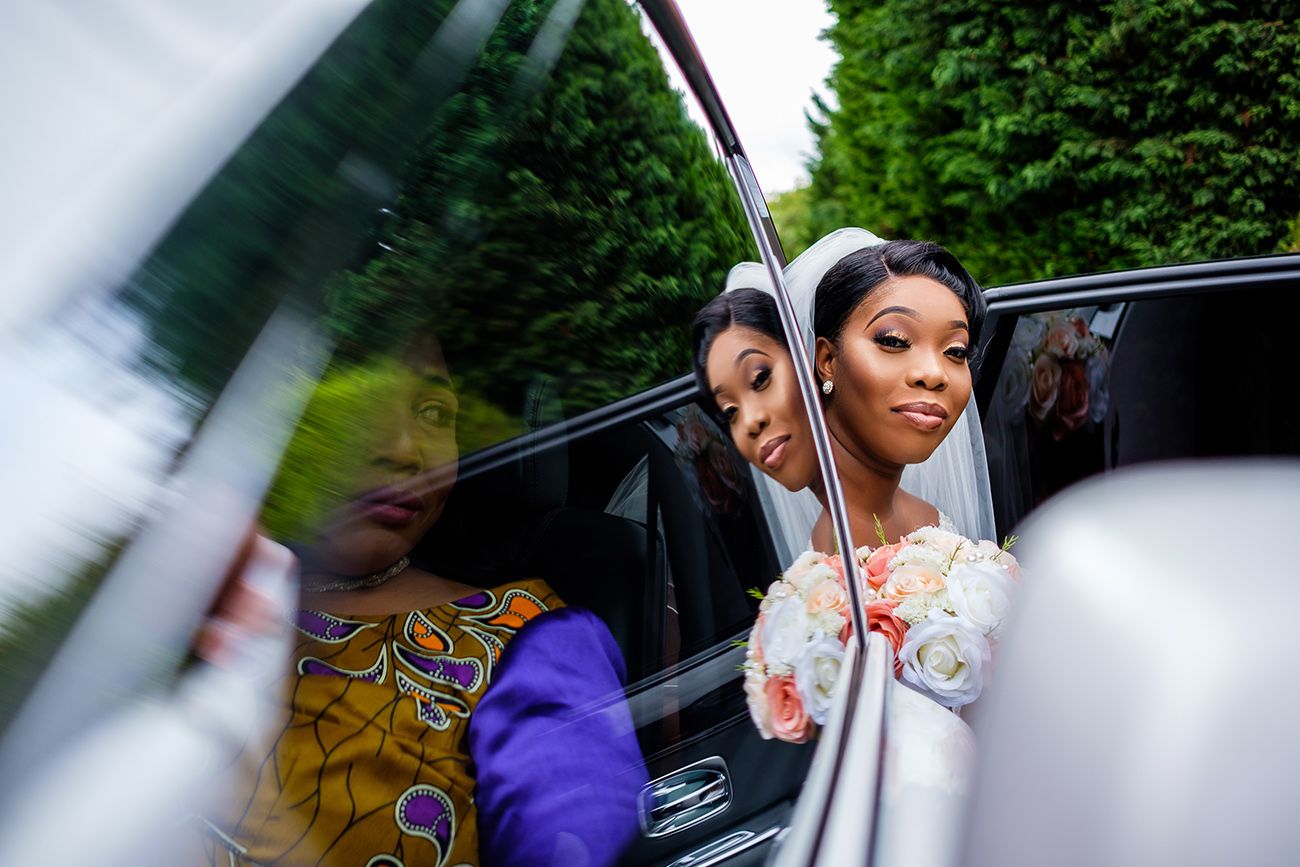 Wedding party arriving in luxury vehicles outside venue with greenery.
