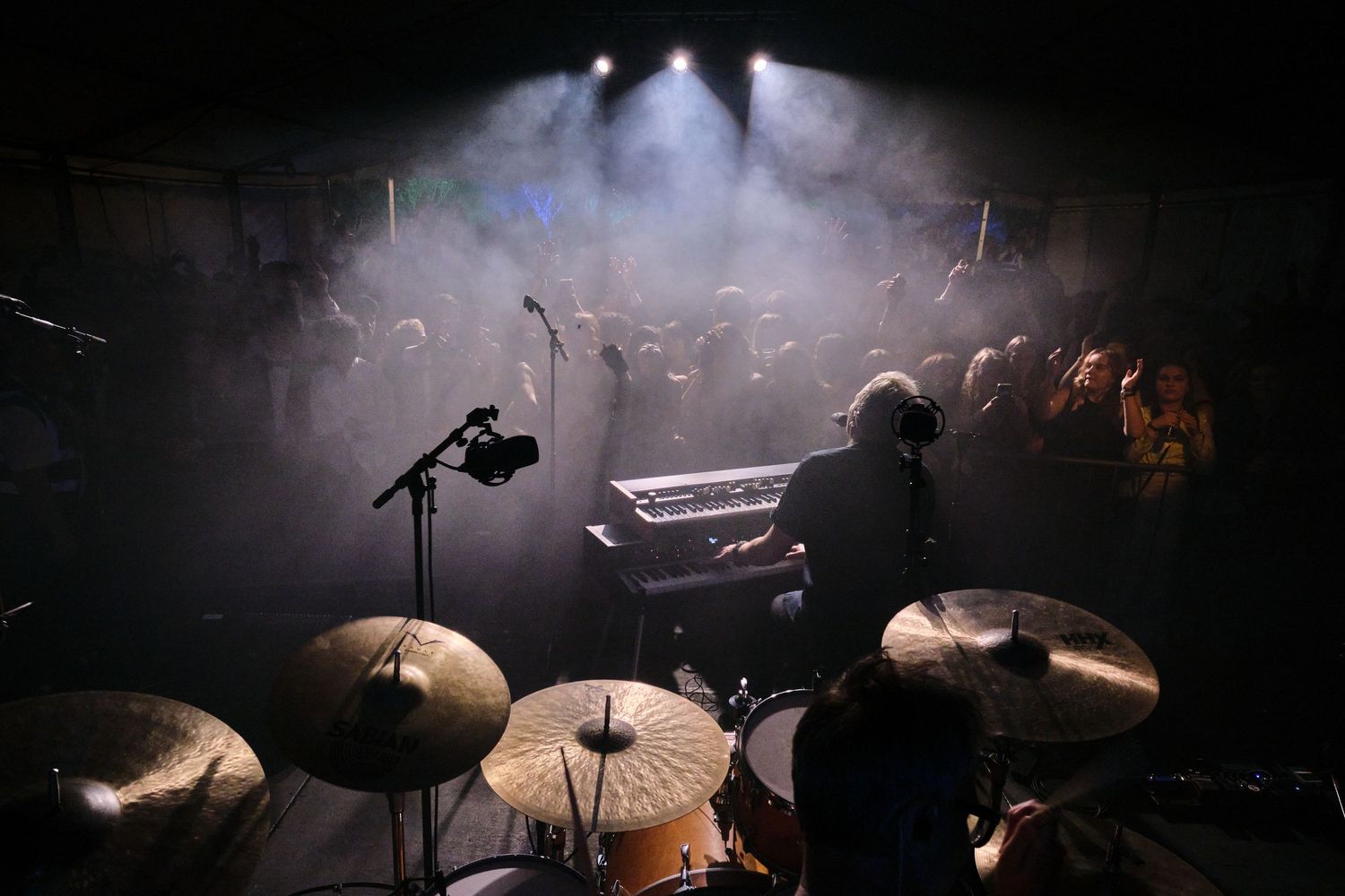 Dramatic silhouette of drums and musical equipment on stage in atmospheric lighting.