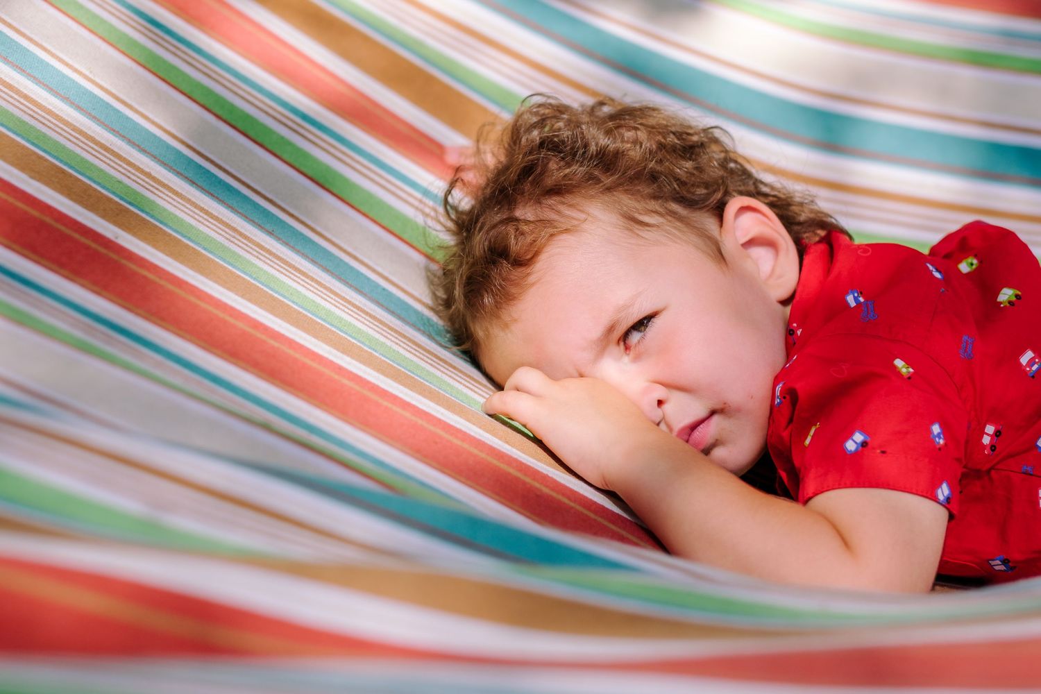 A person resting peacefully in a colorful striped hammock on a sunny day.