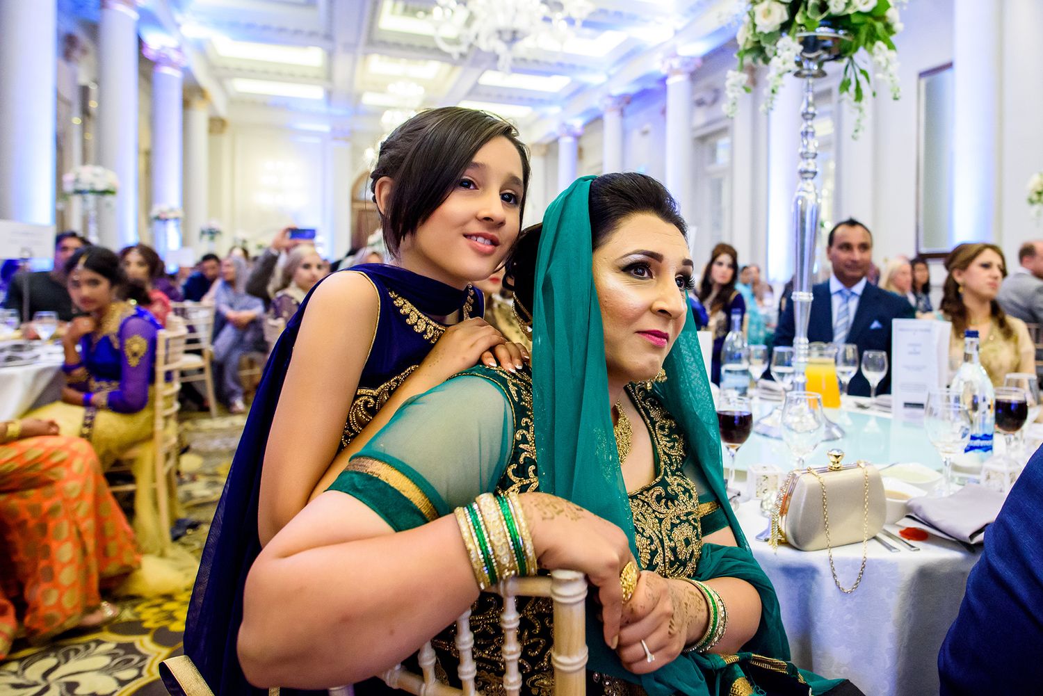Wedding guests celebrating at an elegant reception with traditional South Asian decor and attire.