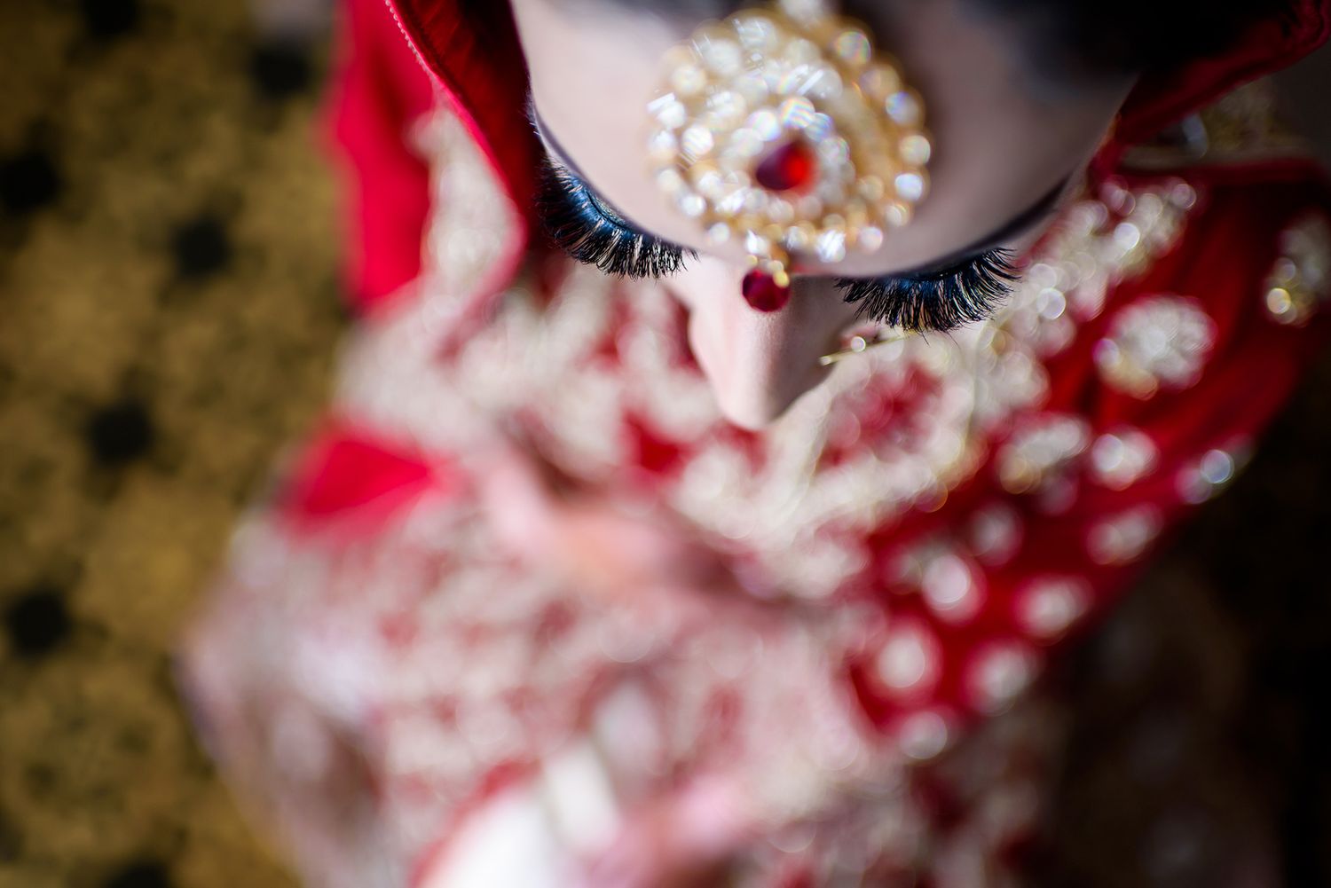 Close-up detail of intricate bridal jewelry and accessories with red accents.