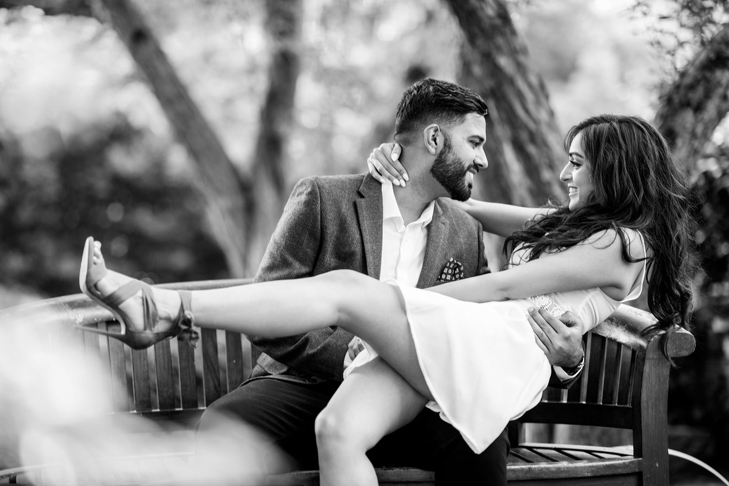 Romantic couple sharing a playful dip pose on a park bench.