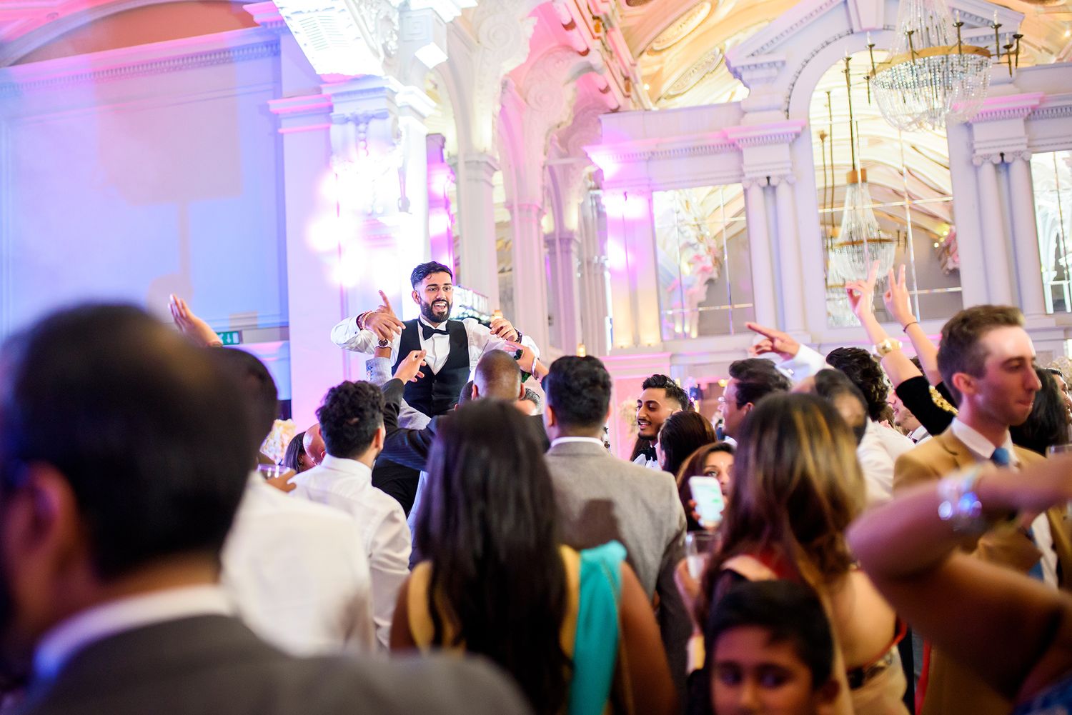 Festive crowd enjoys entertainment in an elegantly lit ballroom setting.