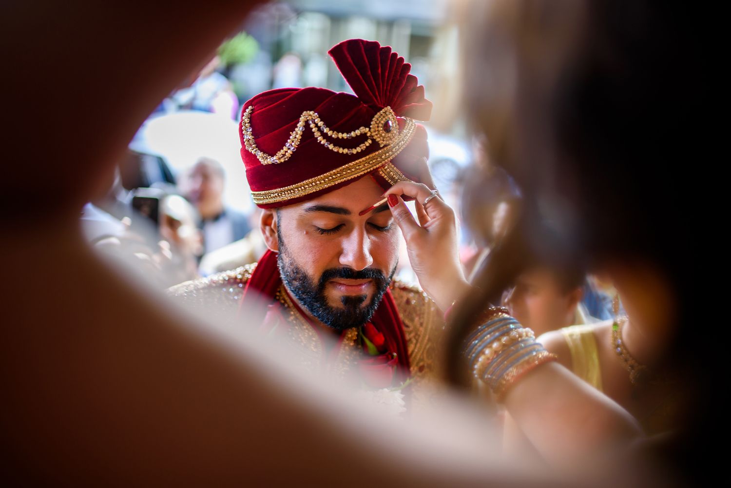 Artistic close-up shot through decorative elements at an Indian wedding ceremony.