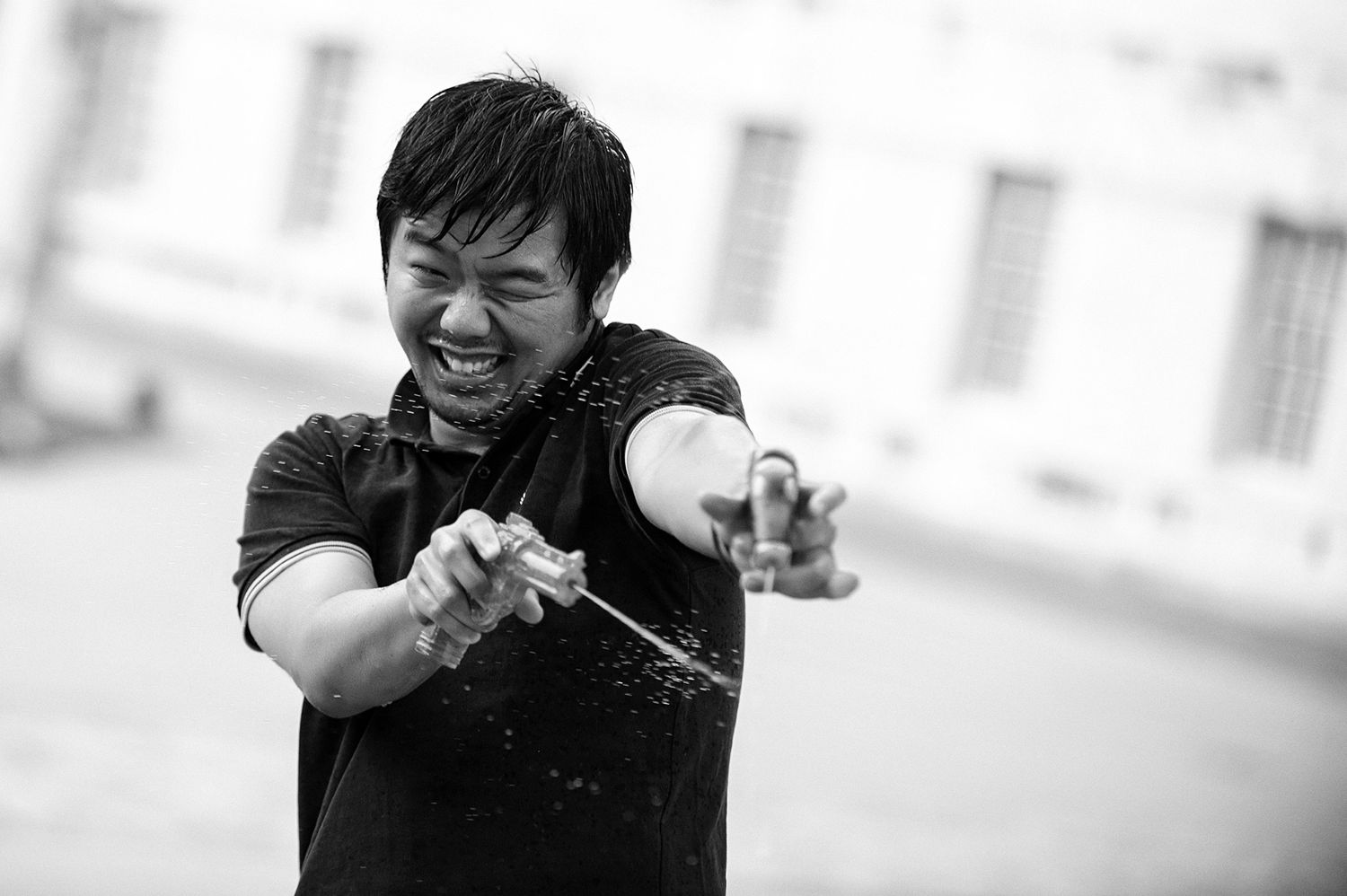 Person striking an animated pose in black and white against classical architecture.