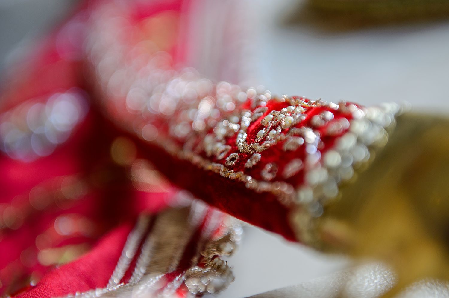 Detailed macro shot of red and gold beaded embellishments on traditional fabric.