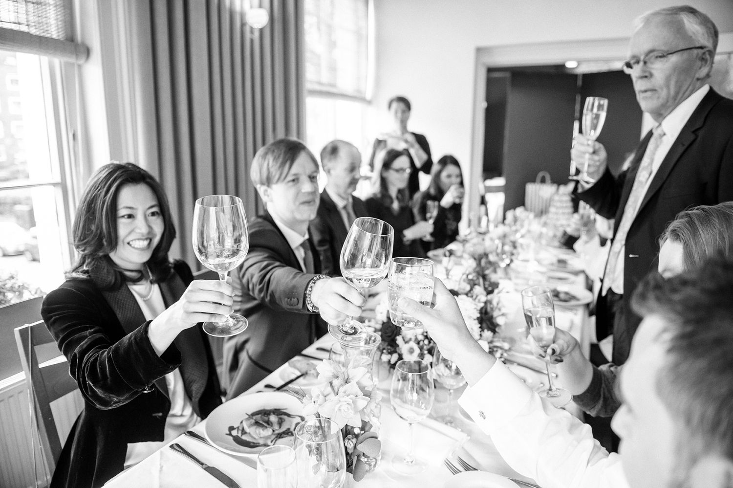 Wedding guests raise wine glasses in a toast during an elegant dinner reception.