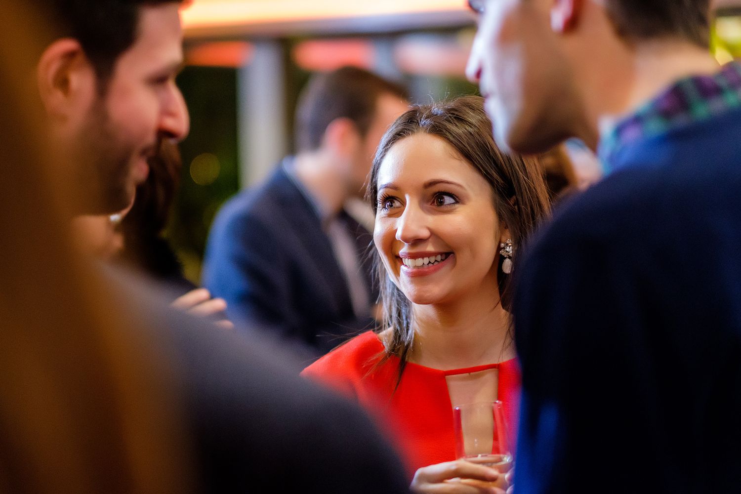People mingling and socializing in formal attire at an indoor business gathering.