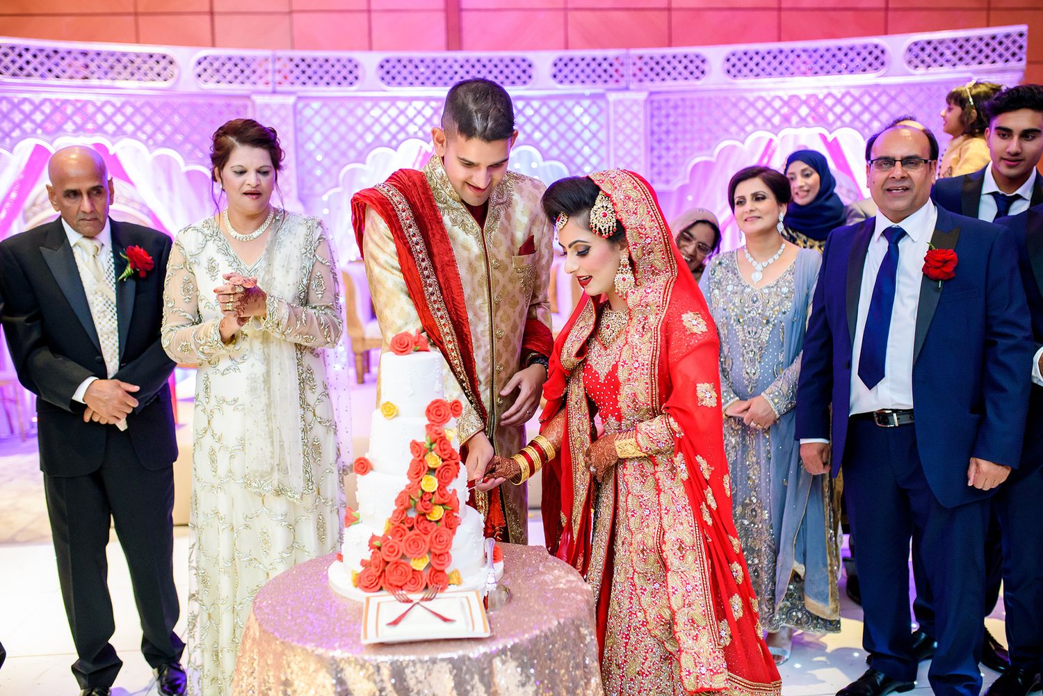 Wedding reception venue decorated with pink lighting and traditional Indian decor elements.