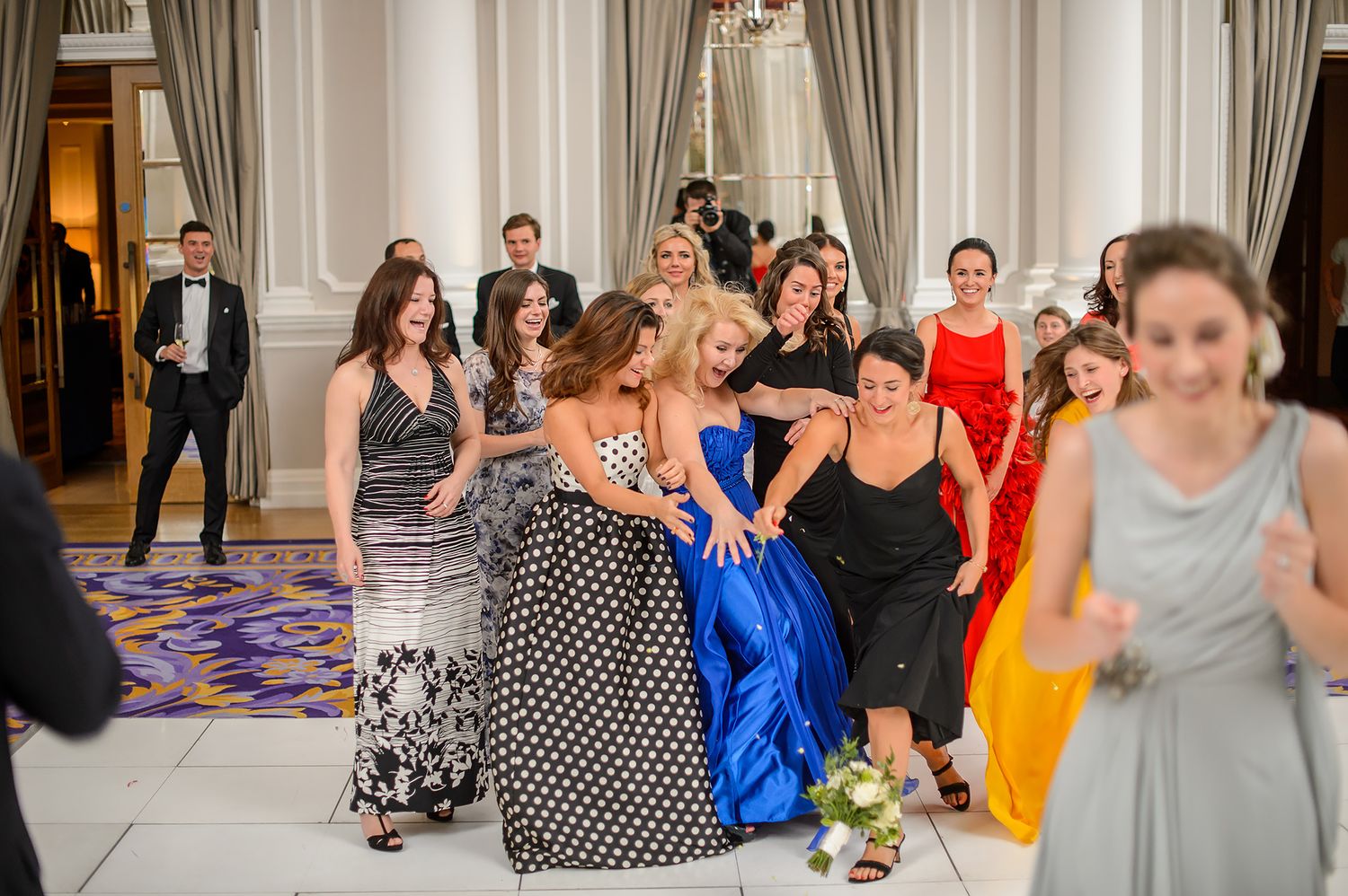 Group celebration with people dancing and socializing at an elegant indoor reception.