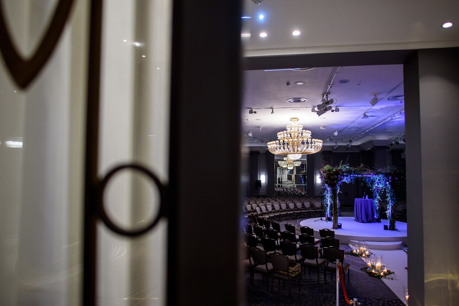 Glimpse of an elegant wedding venue through a doorway showing dark interior with illuminated decor.