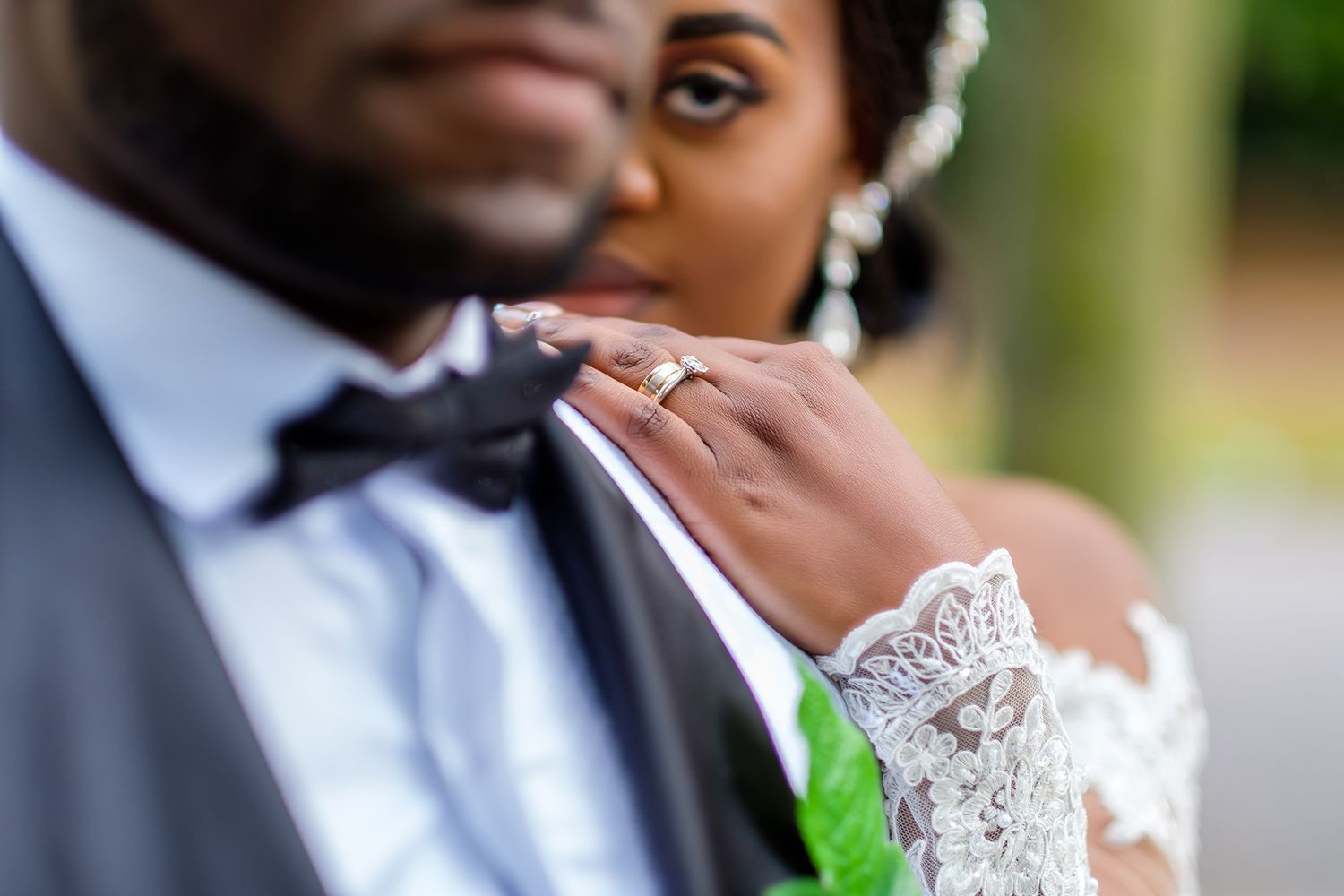 Bride in lace dress and groom in suit sharing tender moments during wedding portraits.