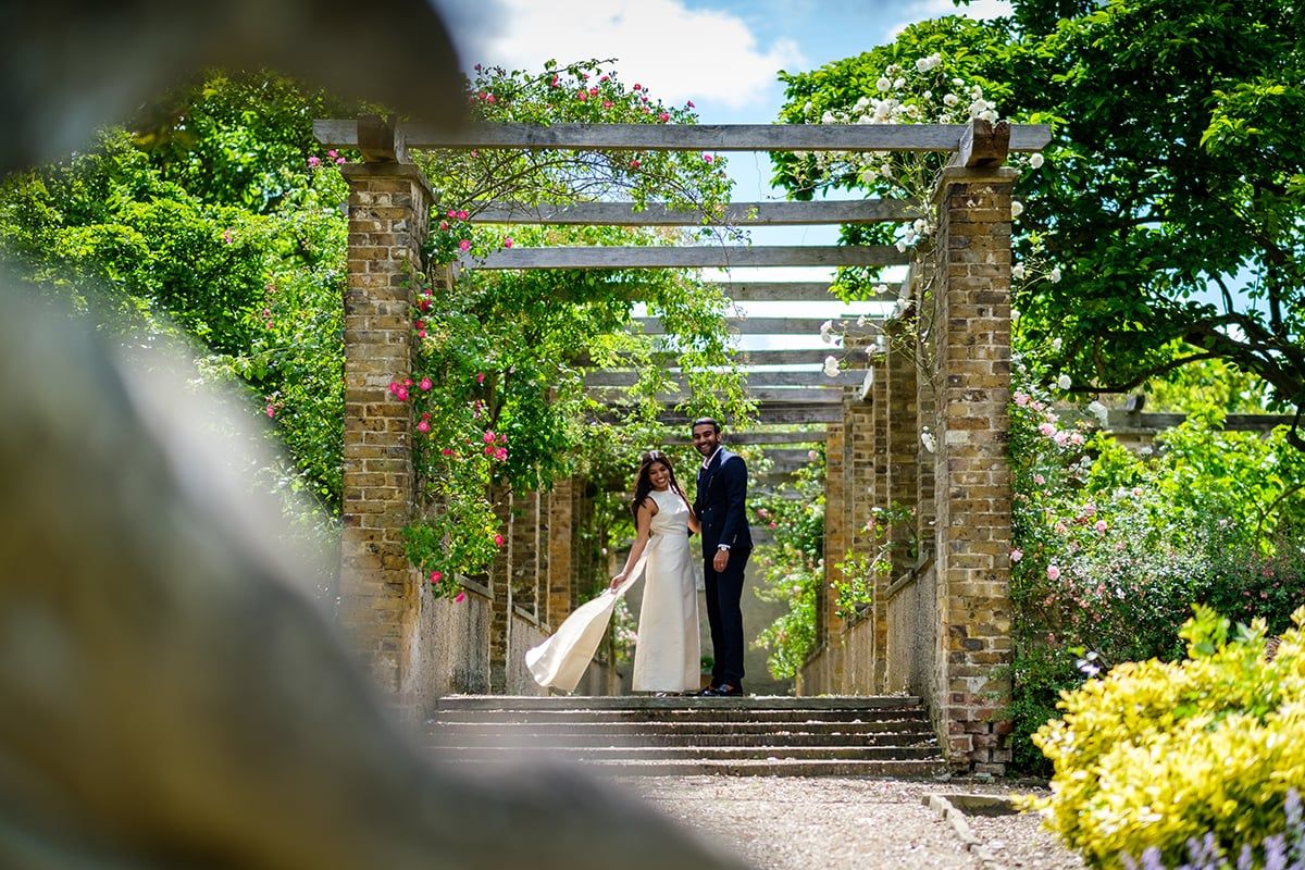 Garden wedding venue with stone pillars and lush landscaping on a sunny day.