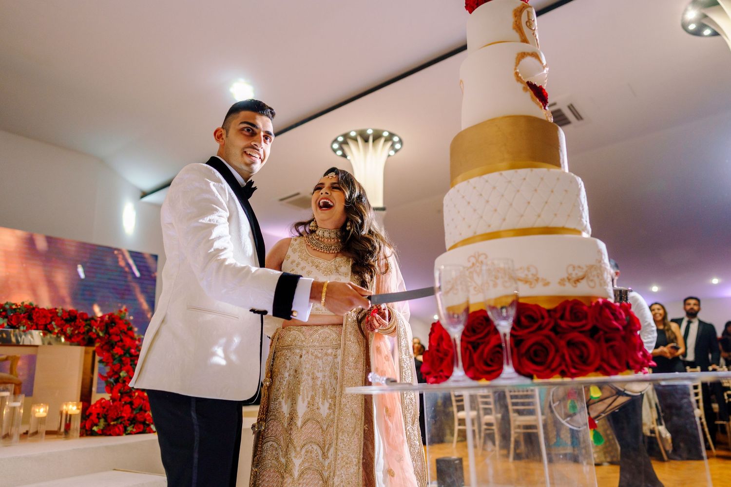 Elegant wedding reception hall decorated with red roses and white table settings.