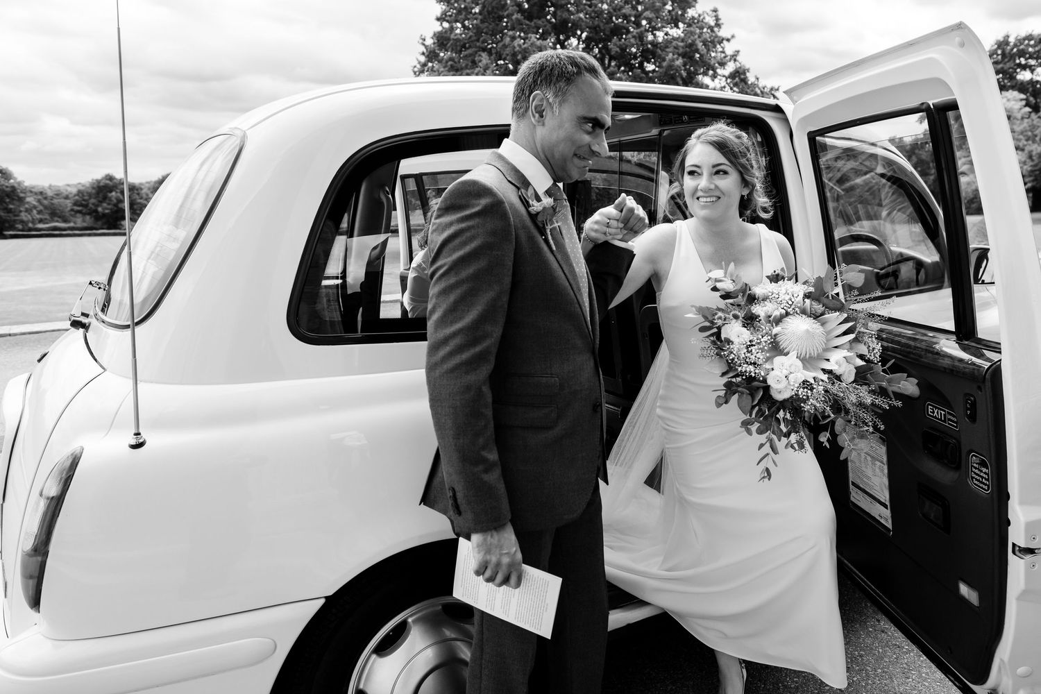 Classic white wedding car arrives with bridal party for the ceremony.