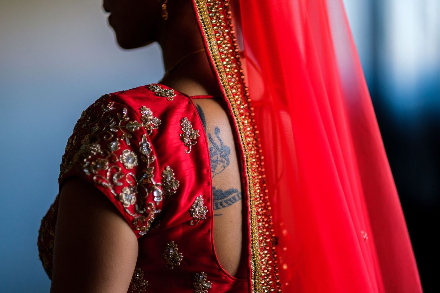 Close-up detail of a red and gold traditional Indian bridal sari with intricate embroidery and embellishments.