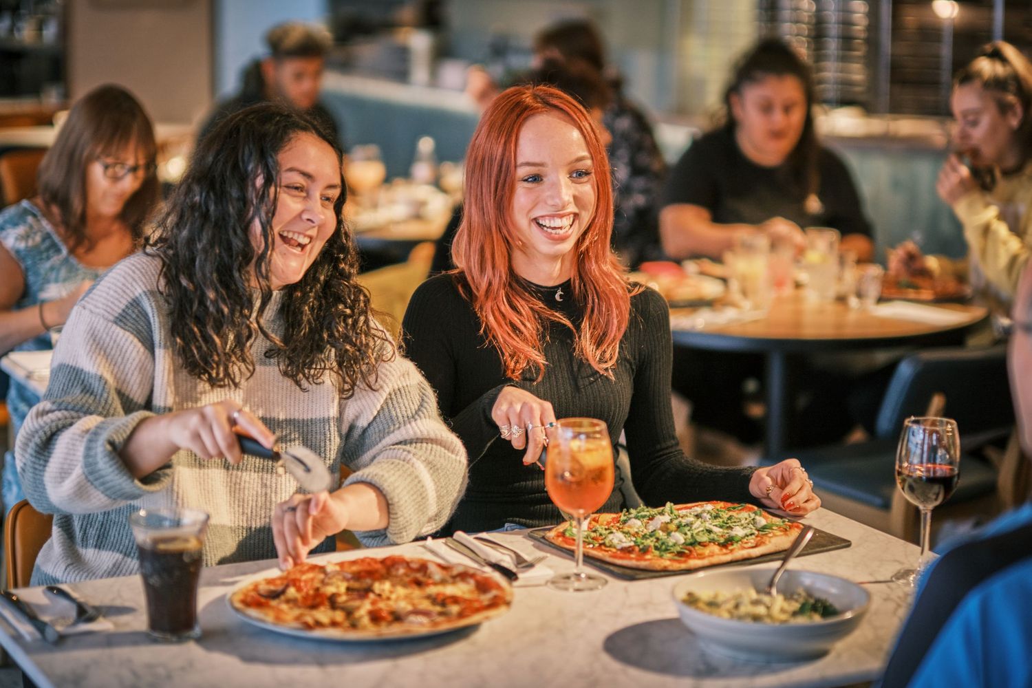 Group dining experience with multiple pizzas shared across restaurant table.