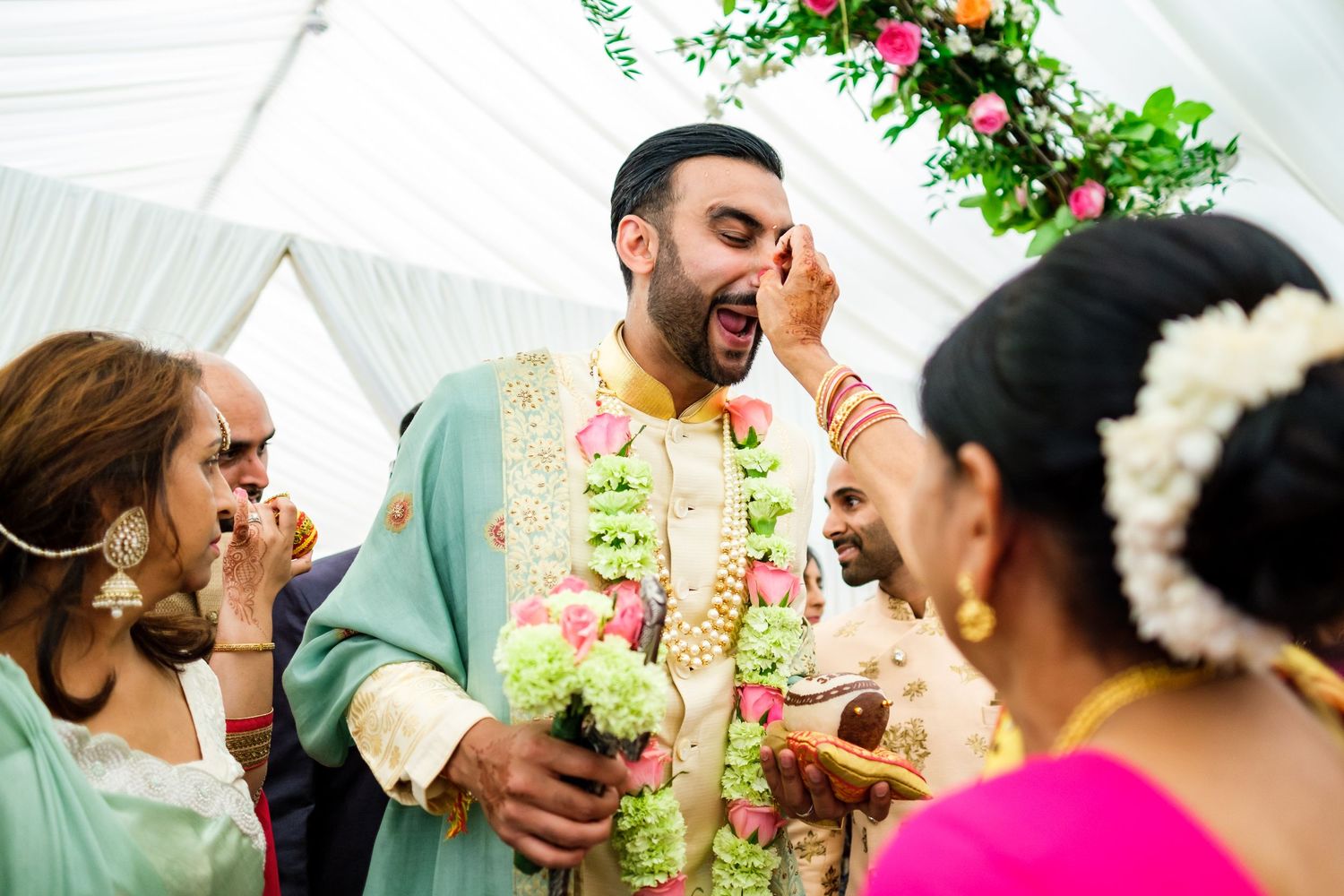 Candid moments of wedding guests laughing and celebrating under floral decorations.