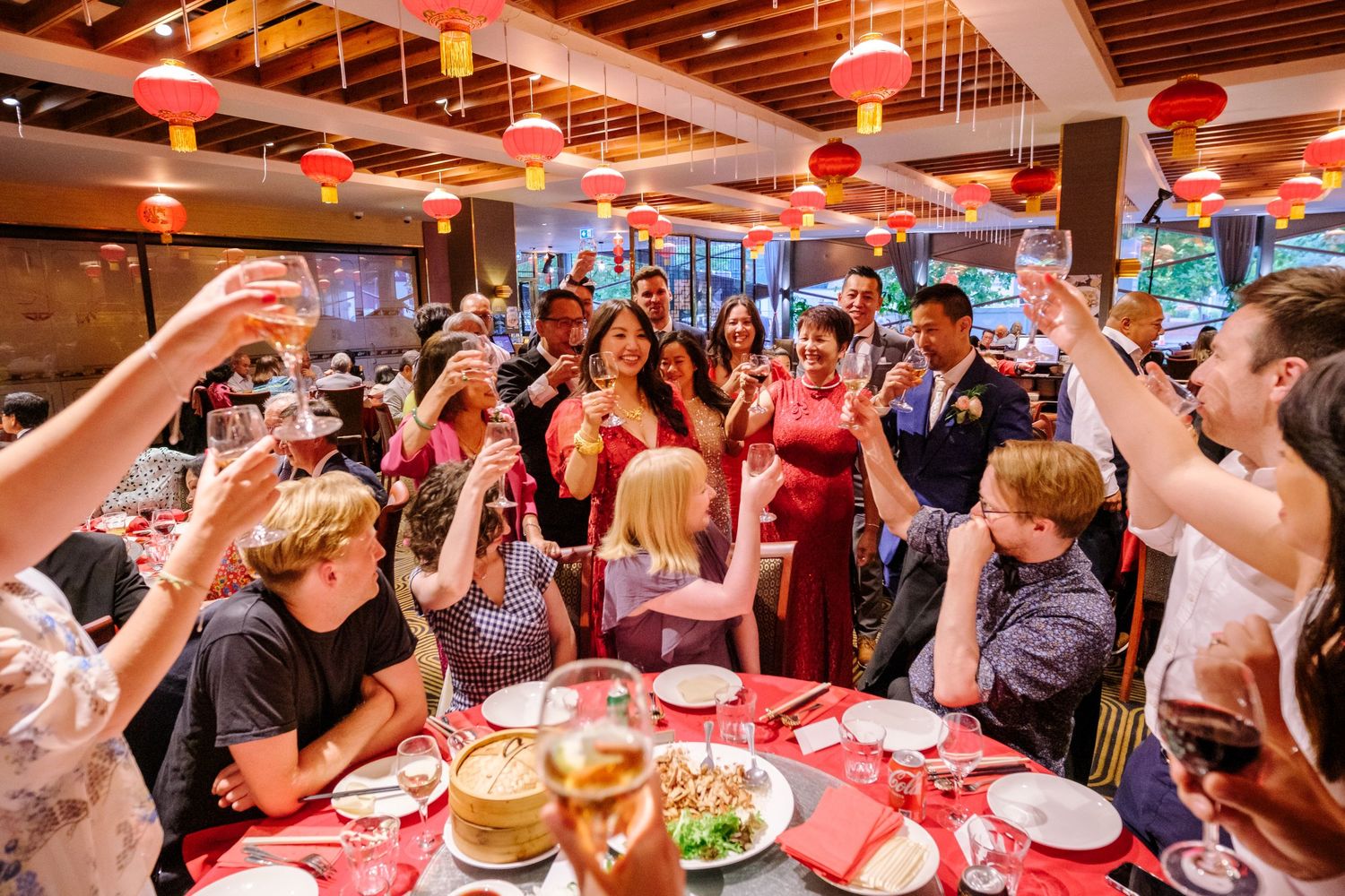 Wide view of a bustling Chinese banquet hall with red lanterns and tables filled with diners.